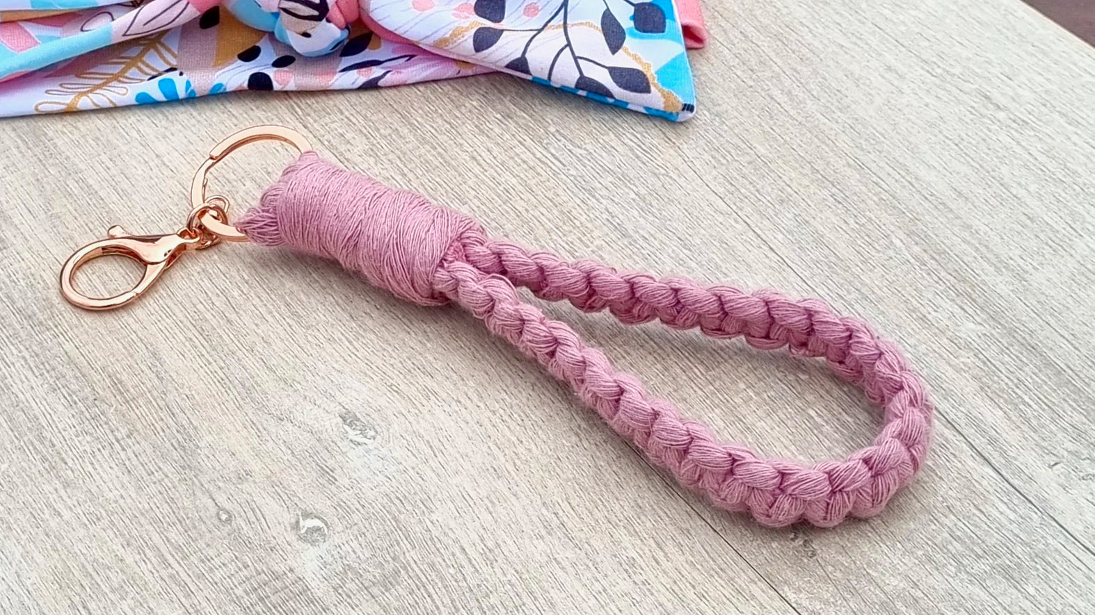 Handwoven Pink Keychain against wooden backdrop.