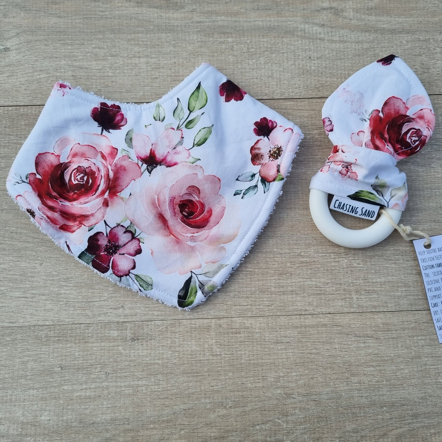 2 Piece Gift Set - Rose Garden against wooden backdrop. Pink watercolour rose design with green leaves on white background. Each set contains 1x Dribble Bib and 1x Teether.