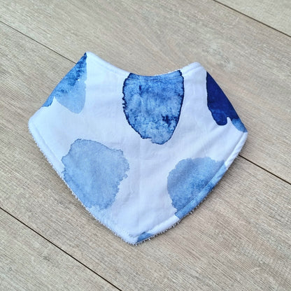 Dribble Bib - Watercolour against wooden backdrop. Blue watercolour patches on white background.