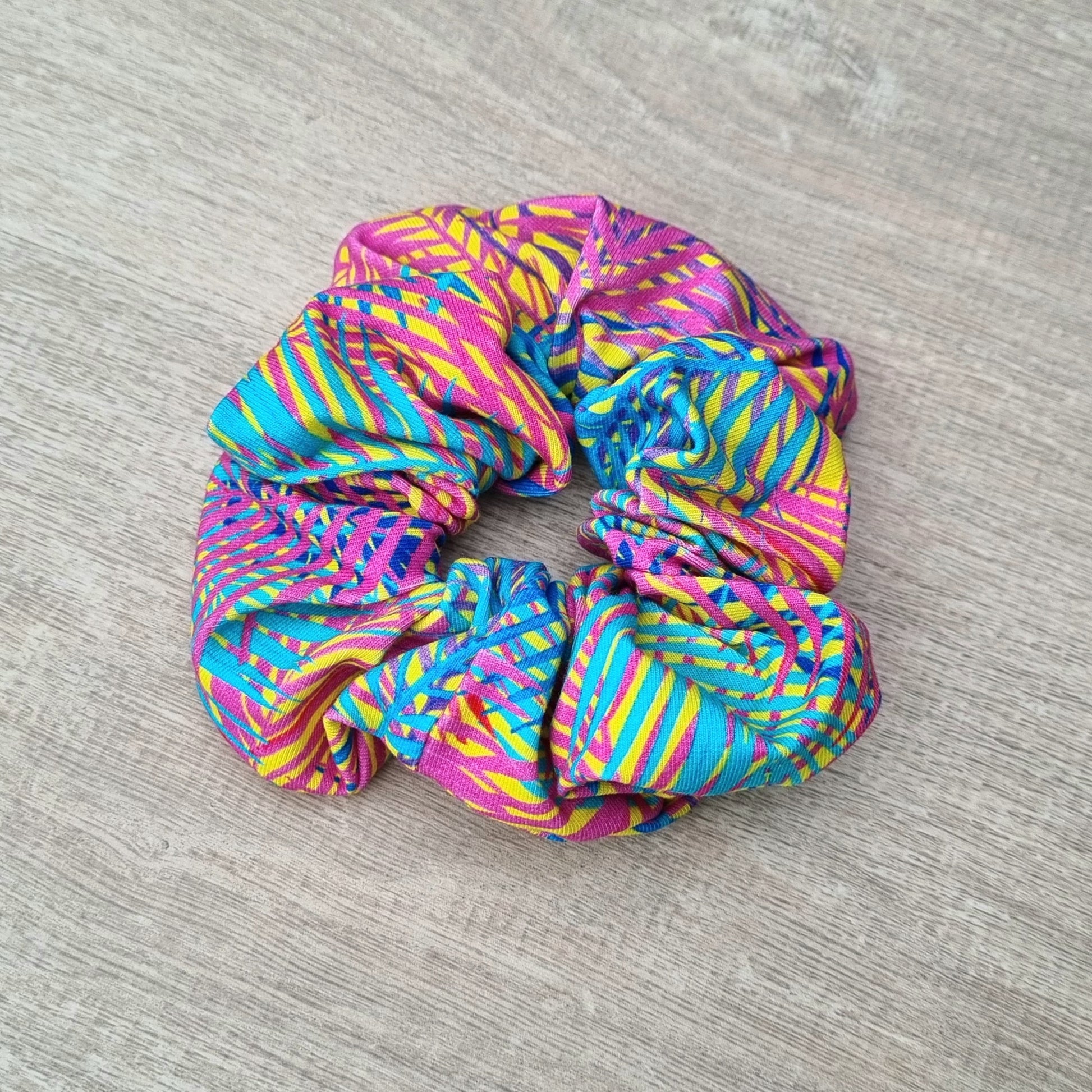 Scrunchie - Rainbow Stripes against wooden backdrop. Blue, navy and hot pink stripes on yellow background.