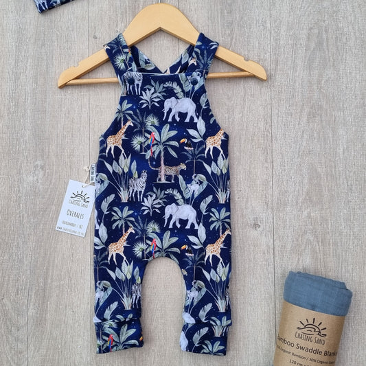 Long Overalls - Night Safari against wooden backdrop. African animal and plant illustrations against navy blue background.