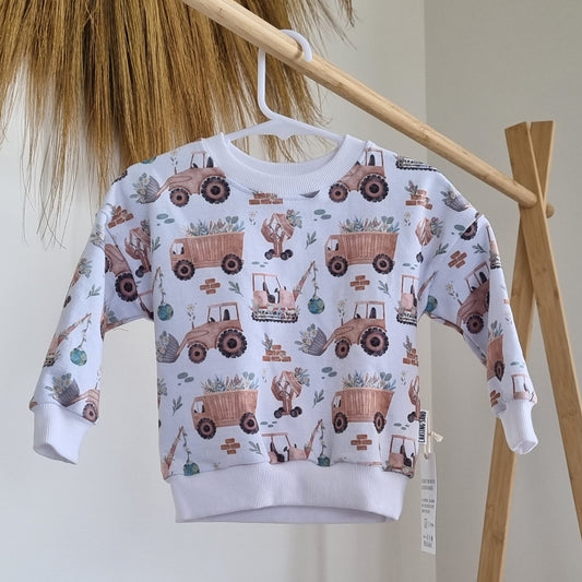 Jumper - Sophie hanging on a wooden rack. Neutral illustrations of construction vehicles moving plants.
