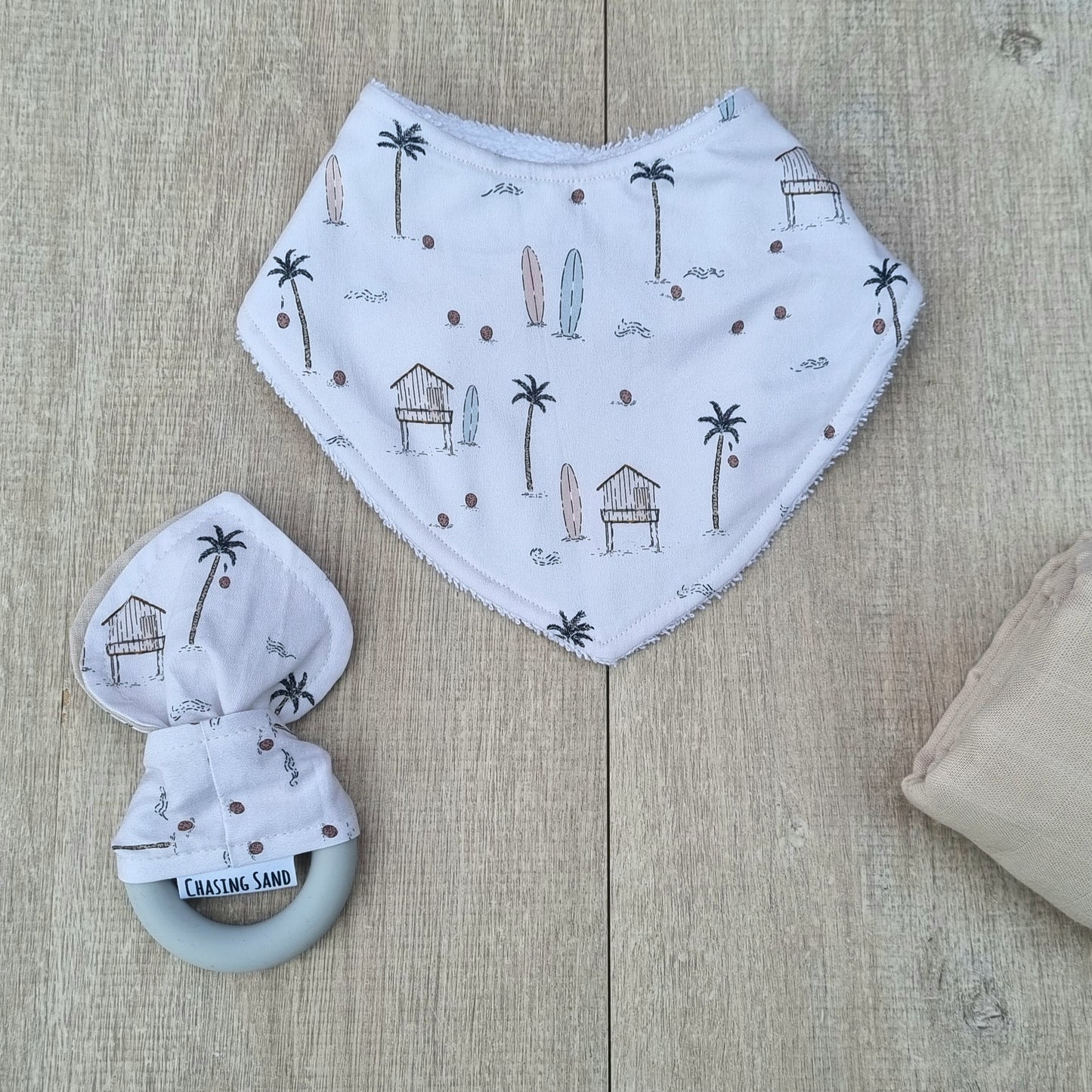 2 Piece Gift Set - Beach Life against wooden backdrop. Beach-themed illustrations on white background. Each set contains 1x Dribble Bib and 1x Teether.