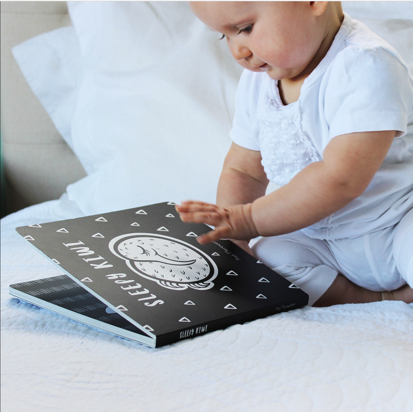 Baby playing with Sleepy Kiwi - Board Book.