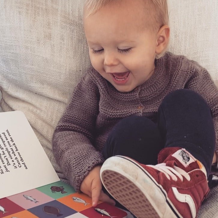 Baby laughing at a colourful page in the book.