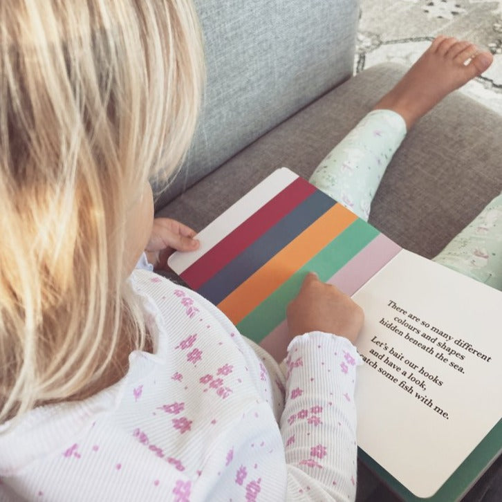 Child pointing to a colourful page in the book.