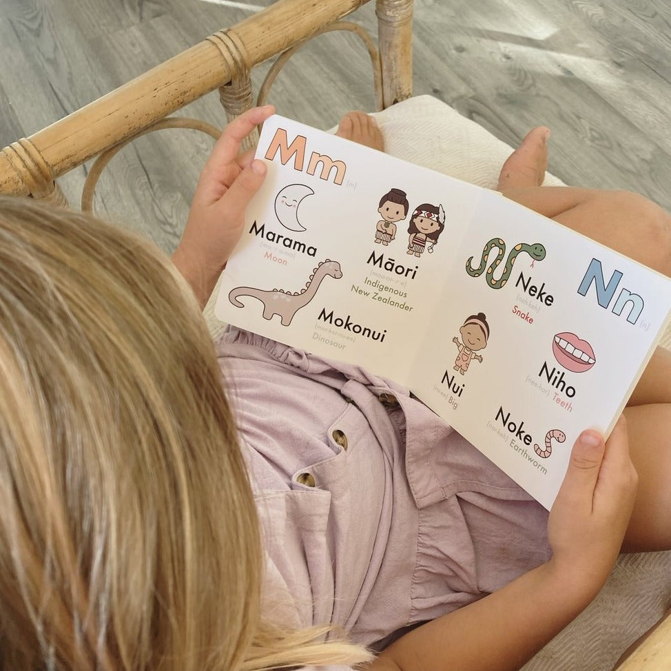 Girl reading a page of Te Reo Māori for Preschoolers - Board Book.