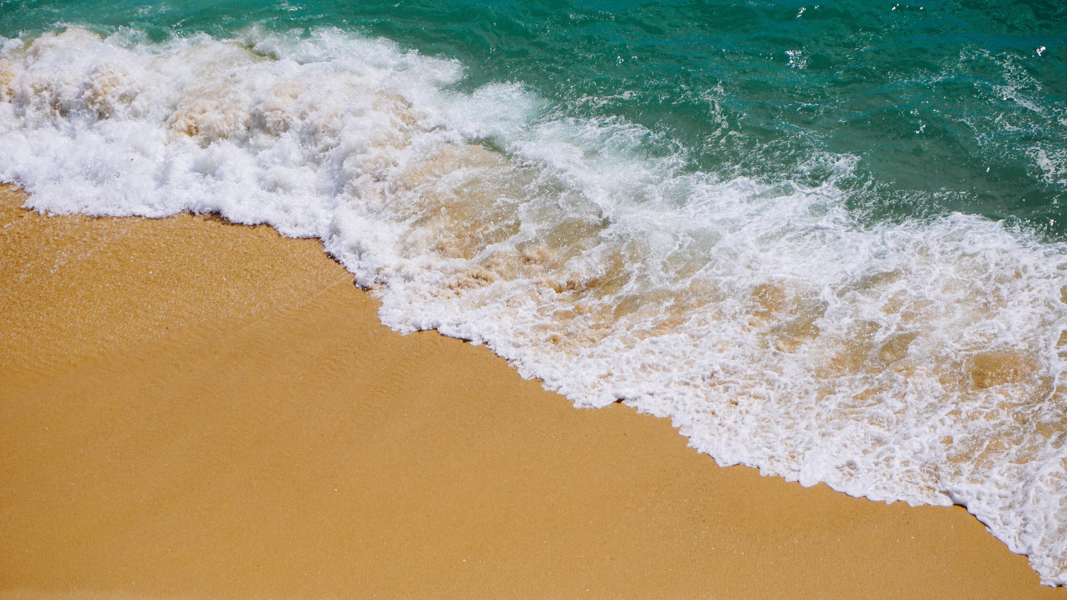 A sandy beach with a wave crashing