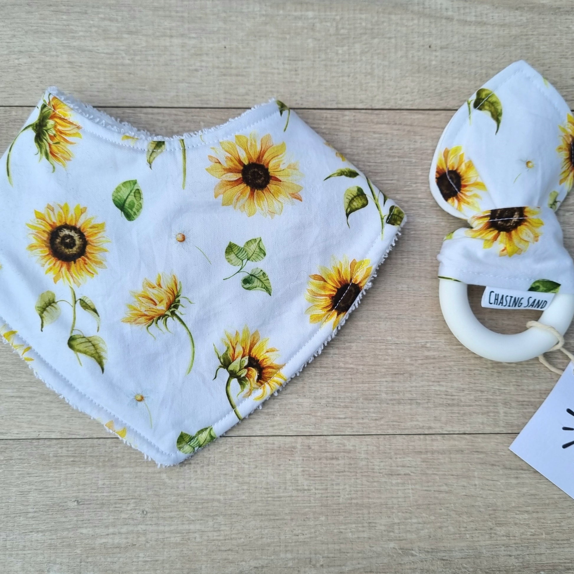 2 Piece Gift Set - Sunflowers against wooden backdrop. Yellow sunflowers on white background. Each set contains 1x Dribble Bib and 1x Teether.
