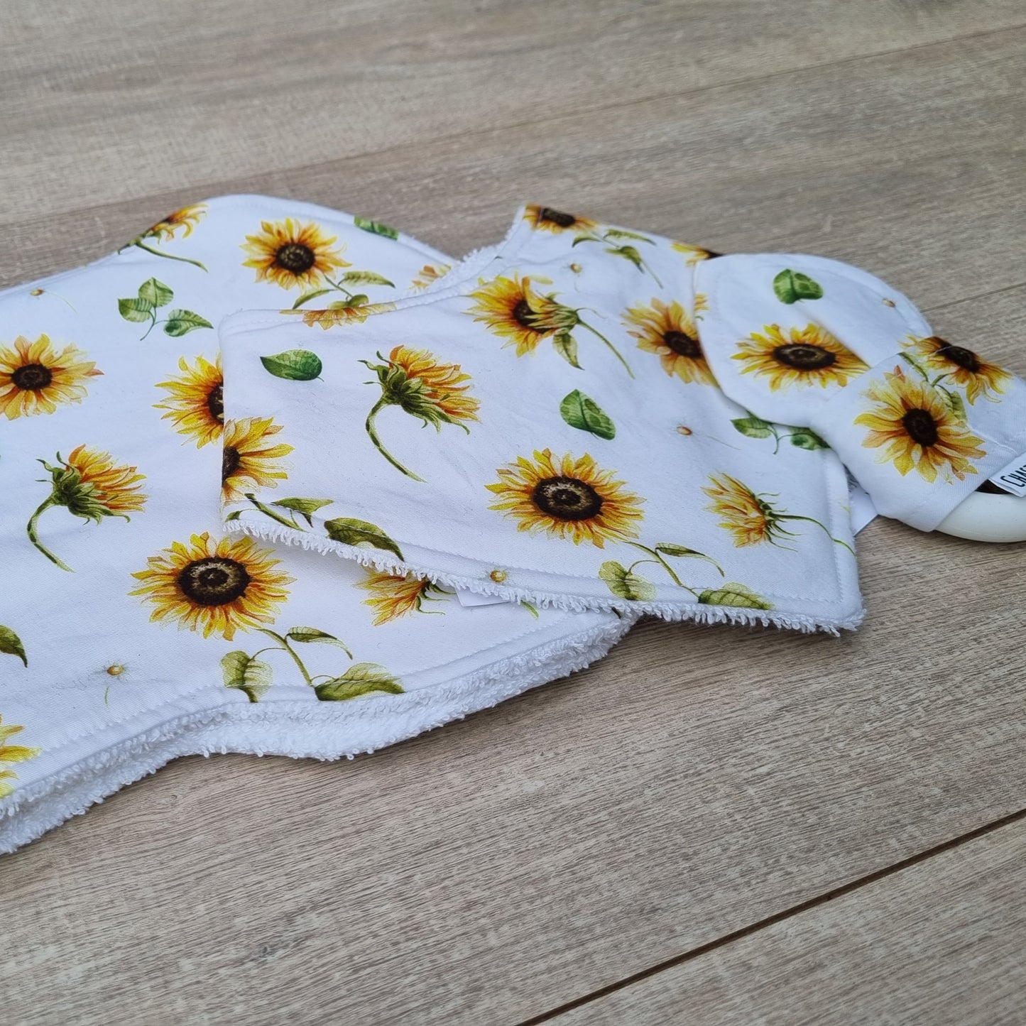 3 Piece Gift Set - Sunflowers against wooden backdrop. Yellow sunflowers on white background. Each set contains 1x Burp Cloth, 1x Dribble Bib and 1x Teether.